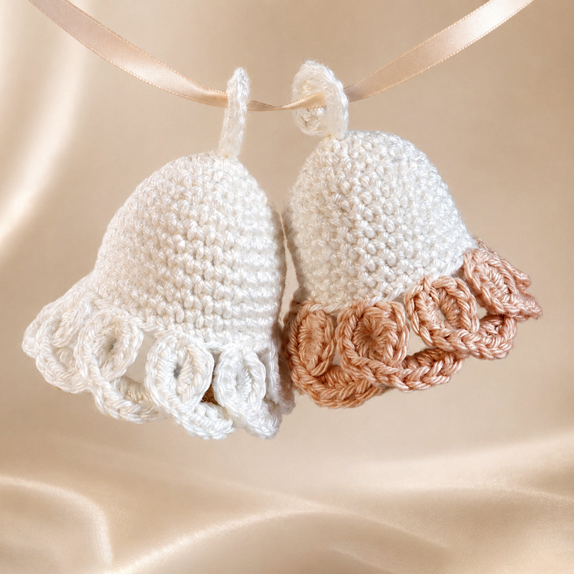 Zwei gehäkelte Glocken „Aurelia“ in Weiß und Beige mit dekorativem Bogenrand.