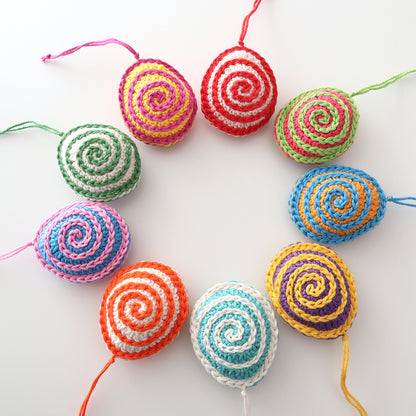 Mehrere bunt gehäkelte Ostereier „Spirelli“ mit zweifarbigem Spiralmuster und Aufhängeschlaufen.
